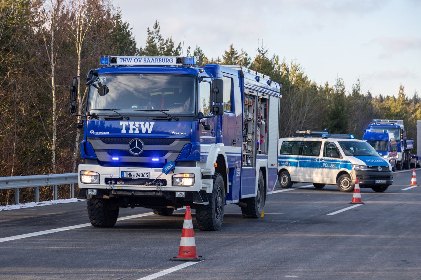 Einsatzfahrzeug der Bergungsgruppe des THW Saarburg sichert mit Blaulicht und Pylonen eine Einsatzstelle auf der Autobahn, dahinter Polizei