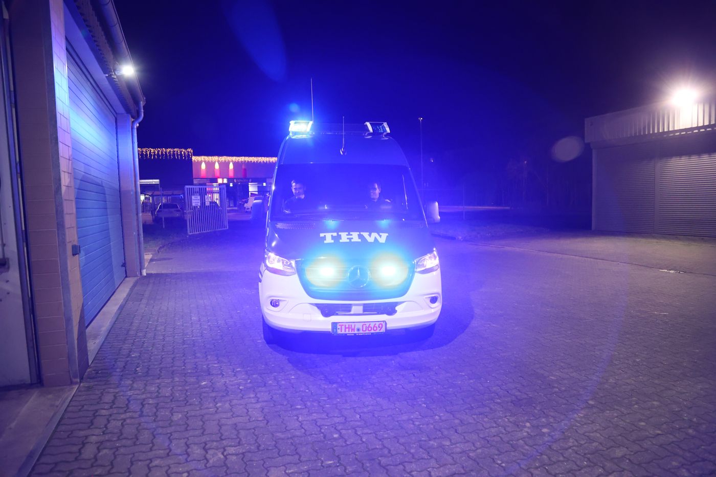 Mannschaftstransportwagen des Zugtrupps mit eingeschaltetem Blaulicht nachts vor der Fahrzeughalle