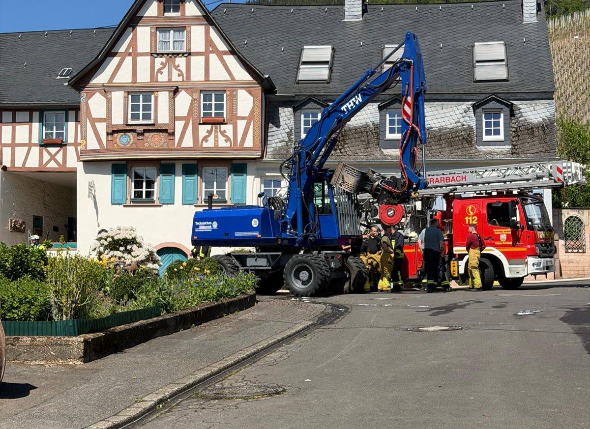 THW-Bagger und Drehleiter der Feuerwehr an einem ausgebrannten Fachwerkhaus