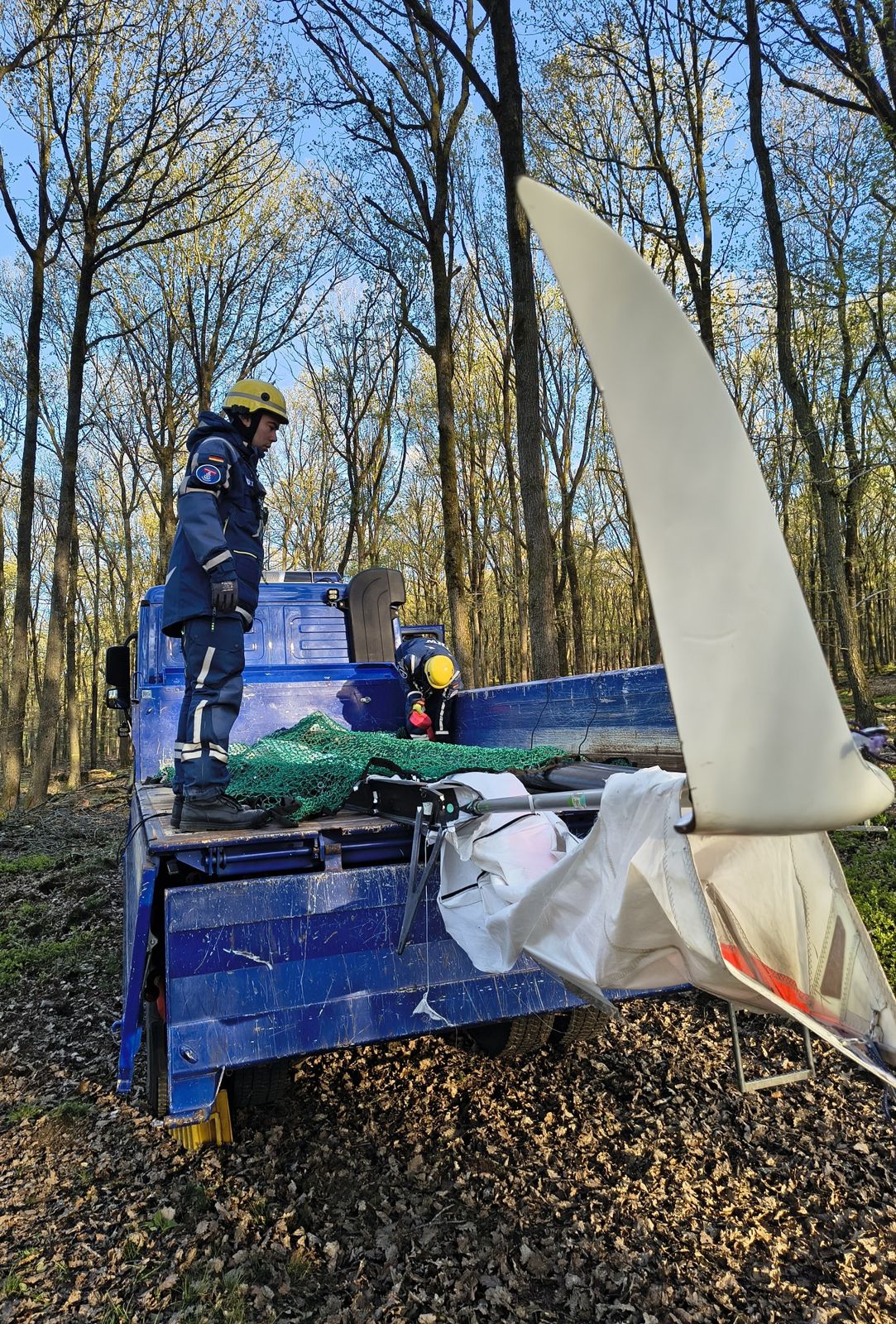 Einsatzkräfte bergen die Tragfläche eines abgestürzten Drachenfliegers im Wald